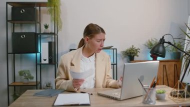 Stressed businesswoman in suit working looking at unpaid bank debt bills, doing paperwork, planning budget calculate finances mortgage payments at office. Displeased freelancer girl throws paper bills