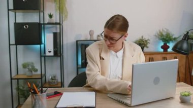 Businesswoman programmer software developer working on laptop at office with anxiety checking time on clock, being in delay, deadline. Concentrated female freelancer business woman worrying to be late