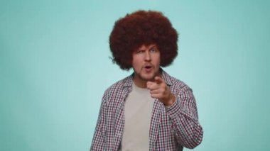 Man showing loser gesture and pointing on you, blaming accusing for unsuccess, expressing disrespect, mocking your failure, bullying abuse. Young guy isolated alone on blue studio wall background