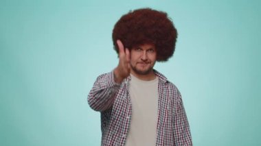 Friendly man in shirt outstretching hand to camera, offering handshake, greeting with kind smile, welcoming showing solidarity, trust concept. Young adult guy isolated on blue studio background