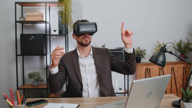 Businessman in suit working using virtual reality futuristic technology VR app headset helmet at home office. Freelancer man busy creating new architecture project. Remote education, study, learning