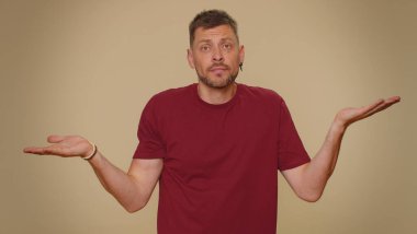 I dont know what to say. Confused handsome young man feeling embarrassed about ambiguous question, having doubts, no idea, being clueless and uncertain. Adult stylish guy on beige studio background