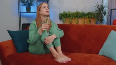 Sad young child kid looks pensive of unrequited love, suffers from unfair situation, drinking champagne. Problem, break up, depressed feeling bad annoyed, burnout, bankruptcy. Girl sits at home room