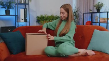 Portrait of happy girl unpacking delivery parcel sitting at home. Smiling satisfied young child kid shopper, online shop customer opening cardboard box receiving purchase gift by fast postal shipping