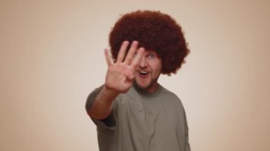 Countdown to holiday birthday celebration. Cheerful young man 30s counting in reverse order from five to one on beige studio background. Win scream, winner gesture. Happy New Year Merry Christmas