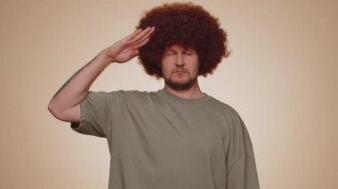 Yes sir. Subordinate, responsible, serious bearded man giving salute listening to order as if soldier, following discipline, obeying, expressing confidence. Young guy boy on beige studio background