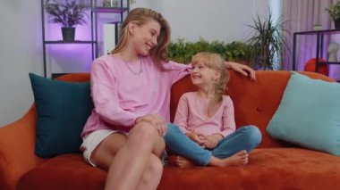 Young loving woman mom talking to little 7s daughter toddler together on couch at home. Preschool kid and mother having warm trustworthy conversation, good relation. Understanding, family bond concept