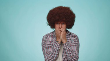 Panic attack. Upset scared frightened bearded adult man biting nails, feeling worried nervous about serious troubles, stress and anxiety disorder, guilty. Young one guy on blue studio wall background