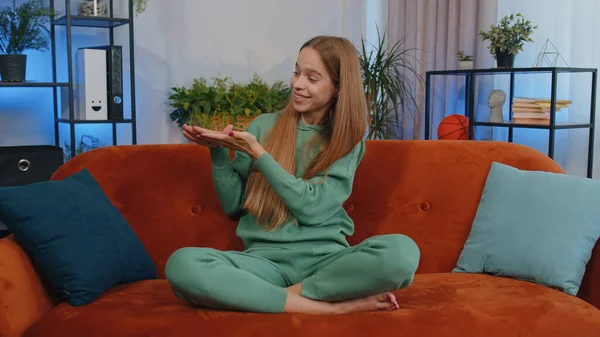 Portrait of cheerful rich teen girl showing wasting or throwing money around hand gesture, more tips earnings, big profit, win lottery, body language, share. Young child kid at home in room on couch