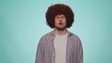 Great job, nice. Cheerful positive happy bearded man in shirt showing thumbs up and nodding in approval, successful good work. Young stylish one guy on blue studio background. People sincere emotions