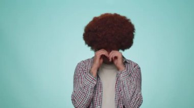 Upset disappointed handsome man in shirt wipes tears and cries from despair, being sad because of unfair things. Young adult bearded guy boy. Indoors studio shot isolated alone on blue background