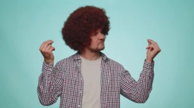 Cheerful rich bearded man in shirt showing wasting or throwing money around hand gesture, more tips dreaming about big profit body language. Young guy posing isolated on blue studio wall background