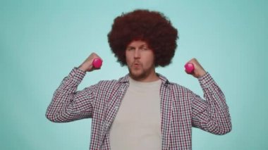 Working out pumping up arm muscles lifting blue dumbbells, practicing pilates healthcare. Man making fitness exercises with dumbbells. Workout for young adult people. Sport motivation. Pink background
