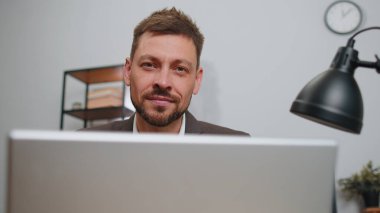 Close-up portrait face businessman freelancer in suit at office workplace, working on laptop computer. Manager freelancer man works on notebook, sends messages makes online purchases watching movies