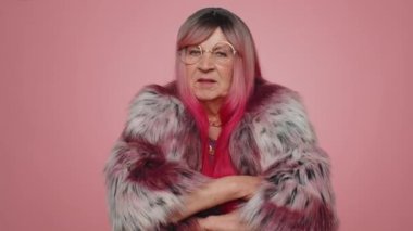 Mutsuz bir kadın nahoş berbat bir fikre tepki veriyor, kötü kaliteden memnun değil, el sallıyor, başını sallıyor hayır, reddet fikri, evlenme teklifini sevme. Yaşlı büyük anne pembe arka planda yalnız.