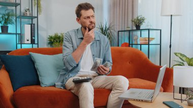 Planlama bütçesi. Zengin ve mutlu bir adam nakit sayıyor hesap makinesi kullanıyor ve evdeki faturaları hesaplıyor. Gelir getiren, kazanan, planlı tatil için para biriktiren, hediyeler alan neşeli genç adam.