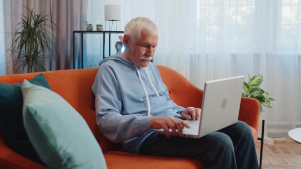 Olgun Yaşlı Bir Adam Oturma Odasında Turuncu Kanepeye Oturur Dizüstü — Stok video