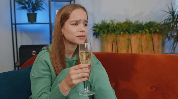 Sad young child kid looks pensive of unrequited love, suffers from unfair situation, drinking champagne. Problem, break up, depressed feeling bad annoyed, burnout, bankruptcy. Girl sits at home room