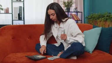 Aile bütçesi planlamak. Gülümseyen genç bir kadın nakit para sayıyor, evdeki faturaları hesaplıyor. Neşeli kız gelirinden memnun ve planlı tatil, hediyeler, gelecekteki harcamalar için para biriktiriyor.
