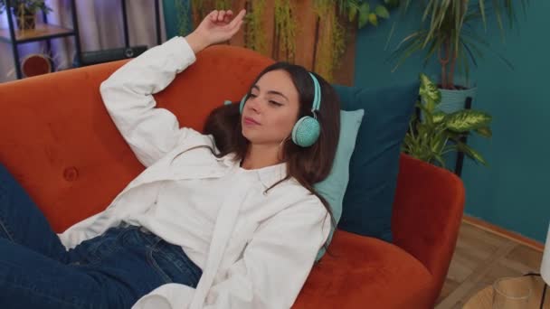 Young Woman Wireless Headphones Relaxing Lying Sofa Home Choosing Listening — ストック動画
