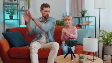 Blogcu baba ve çocuk çocuk oturma odasında oturup müzik dinlemenin, dans etmenin ve sosyal medya için video kaydetmenin keyfini çıkarıyor. Aile internet ağı Wi-Fi bağlantısıyla selfie çekiminin keyfini çıkarıyor