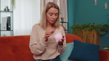 Zavallı Kafkasyalı kız, elinde kumbara ve bir dolarlık banknotla, yetersiz miktarda para tutuyor. Finansal kriz. İflas. Yoksulluk ve yoksulluk. Oturma odasında oturan genç bir kadın.