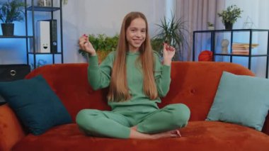 Portrait of cheerful rich teen girl showing wasting or throwing money around hand gesture, more tips earnings, big profit, win lottery, body language, share. Young child kid at home in room on couch