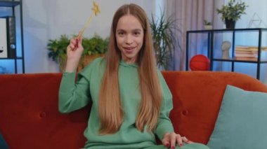 Portrait of student girl child kid magician wizard gesturing with magic wand fairy stick, making wish come true, casting magician spell, advertising holidays sale discount. Young woman at home room