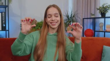 Girl freelancer hold two gold BTC coins at home, successful developer programmer. Woman stock trader earning bitcoins after online monitoring trading operations. Increasing wealth financial prosperity