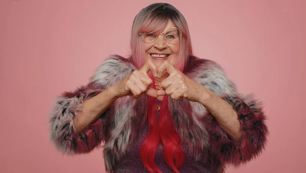 恋の女 スタイリッシュな老婦人の笑顔は心のジェスチャーは 愛のサインは良い感情と同情を表現します シニアおばあちゃん70年代孤立したピンクのスタジオの壁の背景 — ストック写真