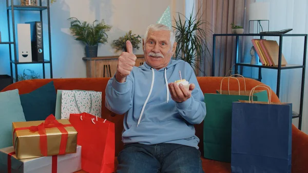 Happy Senior Grandfather Wears Festive Birthday Hat Hold Cupcake Makes — Zdjęcie stockowe