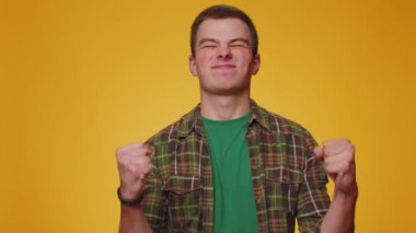 Mutlu, neşeli, gömlekli, bağıran, el kol hareketi yapan bir adam. Başarımı, kazanmamı, doğum günümü, piyango vuruşumu kutladım. Yetişkin erkek çocuk sarı stüdyo duvarında.