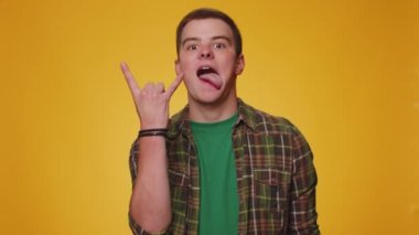 Rock n roll. Neşeli adam, 20 yaşında gömlekli, el hareketi yapan, havalı bir işaret veren çılgın bir ifadeyle evet diye bağıran, dans eden, duygusal olarak sevinen, sarı duvarda tek başına kazanan.