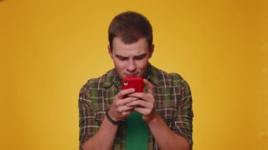 Tişörtlü genç adam cep telefonu kullanıyor, cep telefonuyla yazı yazıyor. Ani piyango sonuçlarını kaybediyor. Kötü talih, kayıp, başarısızlık. Genç yetişkin erkek çocuk sarı stüdyo duvarında tek başına izole edilmiş.
