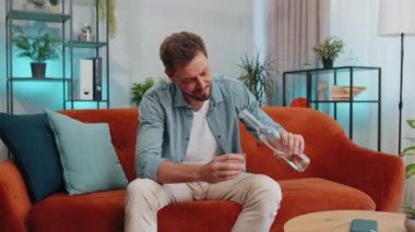 Sad worried young man looks pensive of unrequited love, suffers from unfair situation, drinking vodka. Problem, break up, depressed feeling bad annoyed, burnout, bankruptcy. Guy sitting at home room