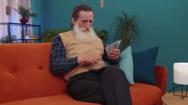 Planning budget. Rich happy senior grandfather counting money cash use calculator and calculate domestic bills at home. Man satisfied of income earnings, win, saves money for planned vacation, gifts