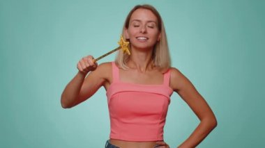 Sihirbaz kadın sihirli değnek ve sihirli değnekle hareket ediyor, dileği gerçekleştiriyor, sihirbaz büyüsü yapıyor, tatil indirimi yapıyor. Mavi stüdyo arka planında izole edilmiş genç cadı kız.