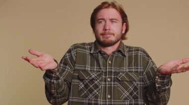 What Why. Sincere irritated adult man raising hands in indignant expression asking reason of failure demonstrating disbelief irritation by troubles. Young confused guy isolated on beige background