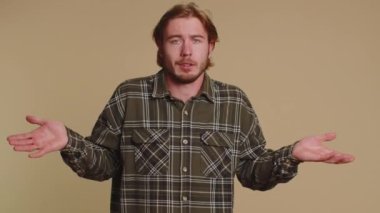 Ne diyecegimi bilmiyorum. Kafası karışmış bir adam, belirsiz bir soru hakkında utanmış, kuşkuları var, hiçbir fikri yok, bilgisiz ve kararsız. Genç yetişkin bir adam bej renkli stüdyo arka planında tek başına izole edilmiş.