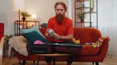 Mutlu sakallı turist bavuluna bir sürü şey dolduruyor, deniz seyahatine hazırlanıyor. Genç adam yola çıkmaya hazırlanıyor, turuncu koltukta kapalı bir odada seyahat planları yapıyor.