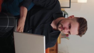 Memnuniyetle kanepede oturup dizüstü bilgisayar başında haykıran mutlu adam zafer jesti olarak ellerini kaldır ve başarıyı kutla piyangodan para kazan. Heyecanlı genç adam internetten iyi haberler alıyor. Dikey görünüm