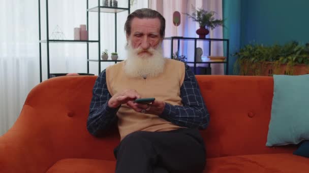 Grand Père Aîné Assis Sur Canapé Utilise Smartphone Sourire Maison — Video