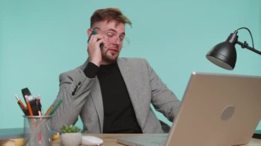 Mutlu sakallı iş adamı patron ofis çalışma masasında oturup telefon görüşmesi yapıyor. Genç serbest çalışan çocuk mavi stüdyo arka planında iş arkadaşıyla mobil sohbetten hoşlanıyor.