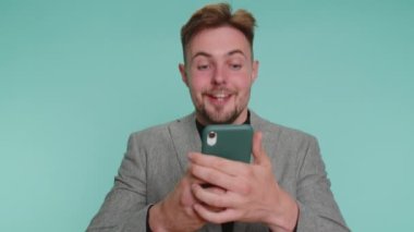 Mutlu, heyecanlı, ceketli iş adamı cep telefonu daktilosu kullanıyor. 