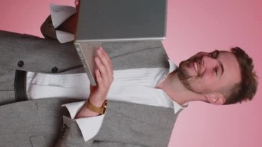 İş adamı web tasarımcısı danışmanı müşteriyle online proje hakkında konuşuyor dizüstü bilgisayardan arama yapıyor. Genç profesyonel yönetici, pembe stüdyo geçmişinde tek başına izole edilmiş. Dikey görünüm