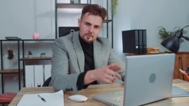 Dislike. Upset businessman in suit working on laptop computer at home office thumbs down sign gesture, expressing discontent, disapproval, dissatisfied bad work. Displeased serious male freelancer man