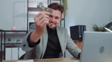 Businessman stock trader earning bitcoins after online monitoring trading operations. Increasing wealth, financial prosperity. Professional freelancer man working on laptop at office workplace desk