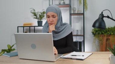 Tesettürlü bir iş kadını, ofis masasında yaratıcı bir proje için karar vermeyi düşünüyor. Kendine güvenen Müslüman serbest çalışan kız laptoptaki analitik raporlara bakmakla meşgul.