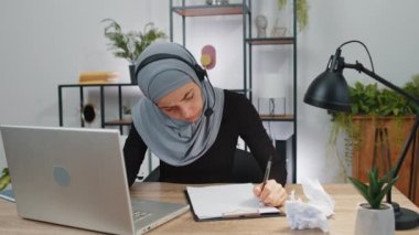 Evde çalışan kızgın müslüman kadın kağıt fırlatıyor, işte sinir krizi geçiriyor, migain, baş ağrısı, stres yönetimi, zihinsel sıkıntı problemleri, kendini kaybediyor, başarısızlığa tepki veriyor