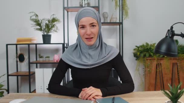 Мусульманская Бизнесвумен Хиджабе Работающая Ноутбуке Дружелюбно Улыбается Камеру Жестикулирует Привет — стоковое видео